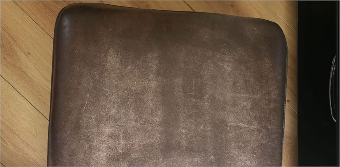 Leather chair seat pad with faded, patchy colour worn through the centre